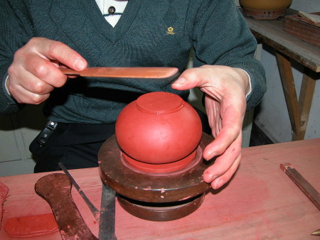 55、用“小竹插”輕輕地拍壓“圈足底片”，並調整將之務必黏在壺體身筒的最中間。