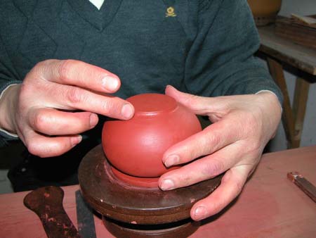 57、用手指整順壺底圈足的外接合處。