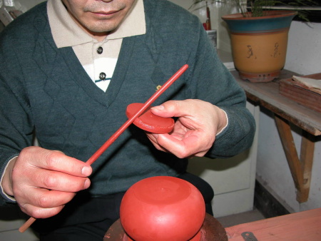 59、用沾好稀泥的稀泥棒，沾黏稀泥平均的塗佈在“壺頸圈片子”的上邊周圍。