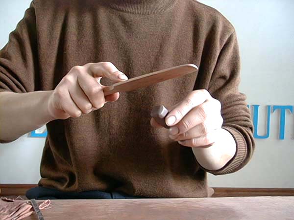 29、以木拍子碾转出一制作“盖钮”用大小的圆泥条，再以左手持泥条，右手持小拍子，轻柔的拍整出方形，想要形式的盖钮，然后盖钮切下待用。